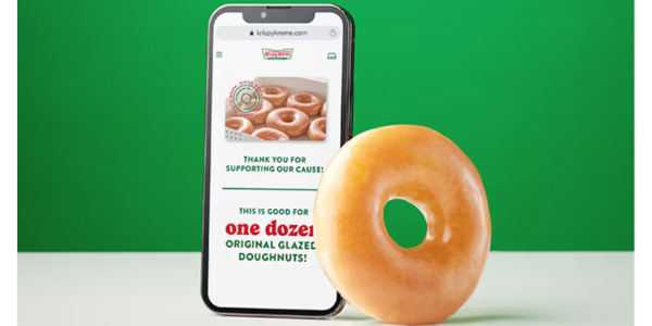 Krispy Kreme fundraising website on a mobile phone with a glazed donut leaning against the phone