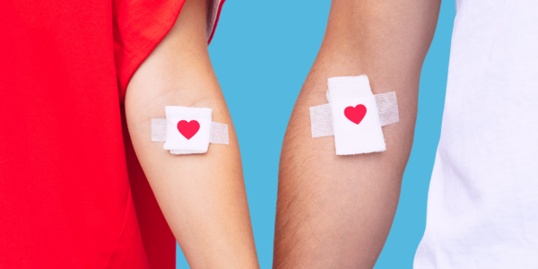 the arms of a woman and a man who have just donated blood - white bandages with red hearts on them