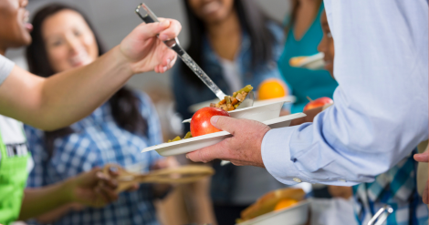 a volunteer serving a meal at a community kitchen