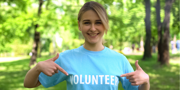 happy teen girl pointing to her light blue Volunteer tshirt