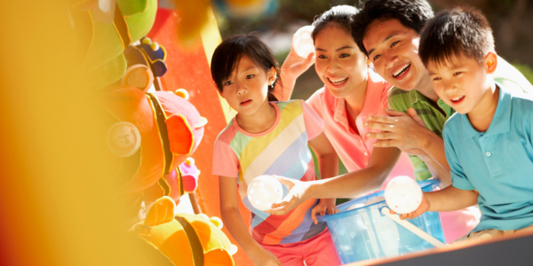 two parents with their elementary-aged daughter and son playing a carnival game