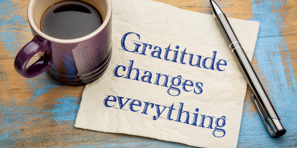 Gratitude changes everything written on a napkin next to a coffee cup and pen