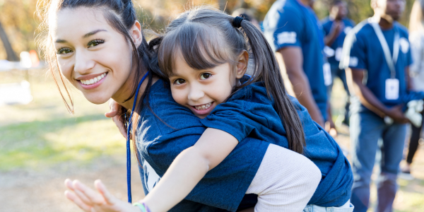 young adult Hispanic woman with female hispanic child on her back