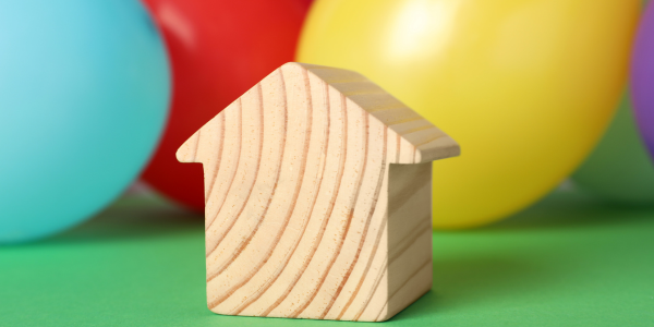 small wooden block house sitting in front of party balloons