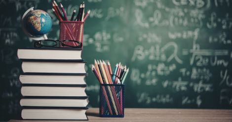 teacher's desk with books, pencils in a pencil holder, glasses, and a tiny globe